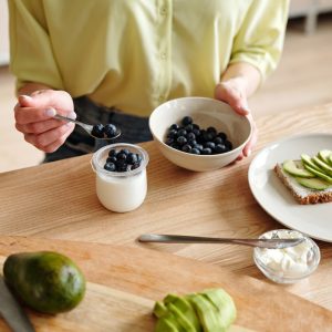 An elderly woman a yogurt with blueberries