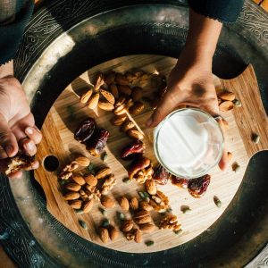 a tray of different kinds of nuts and a glass of milk