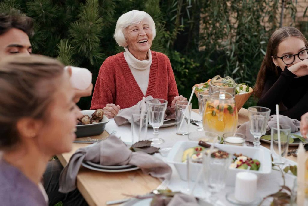 smiling elderly woman eating with family