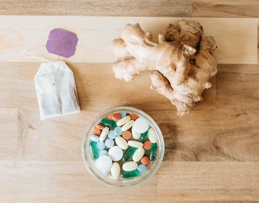 bowl of pills and ginger root on a table