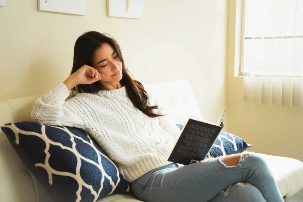 woman sitting on a couch while reading a book