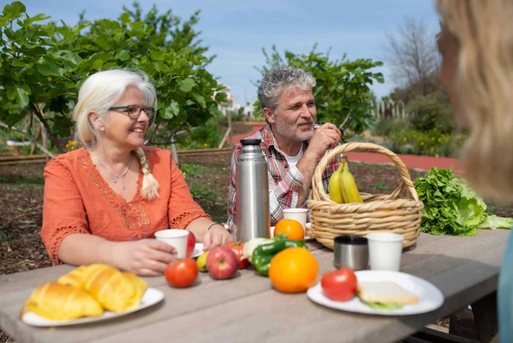 elderly couple eating fruits and vegetables at the garden