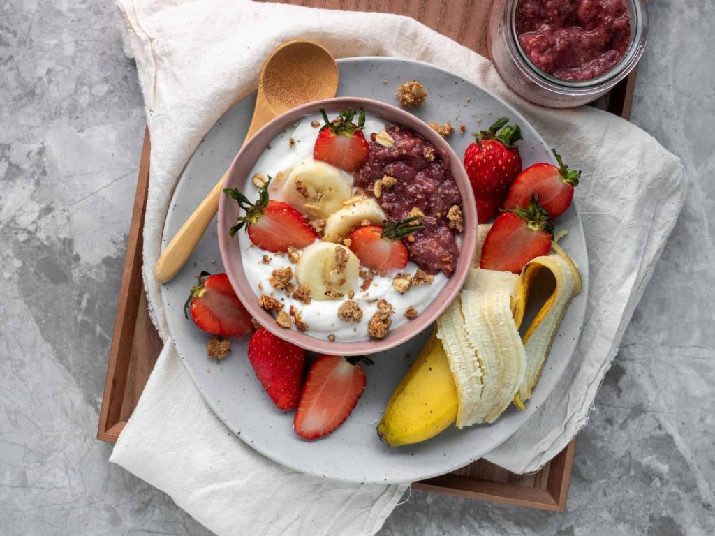yogurt with sliced fruits on white ceramic plate